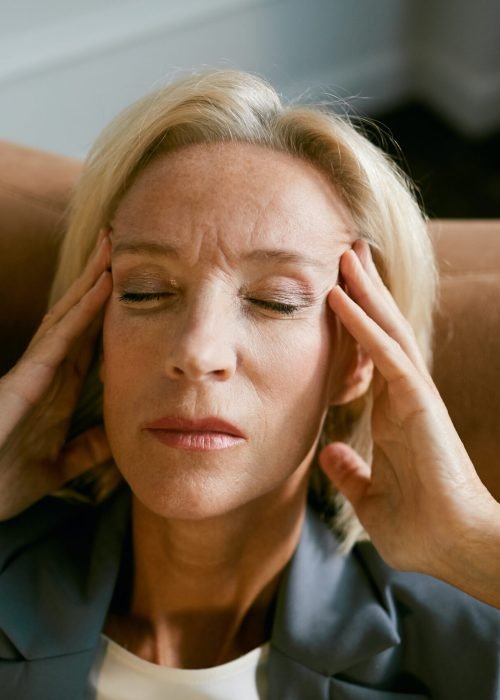 Mature Businesswoman Suffering from Headache Portrait of stressed mature businesswoman rubbing temples suffering from headache while sitting in chair with eyes closed, copy space